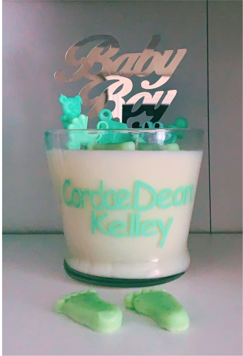 Green 16oz baby shower candle with 'Baby Girl or Boy' topper, wax baby feet, rubber duck, and baby-themed decorations (decorations may vary on availability). Includes an instruction card and customizable label for baby's name. Scent: Baby Powder